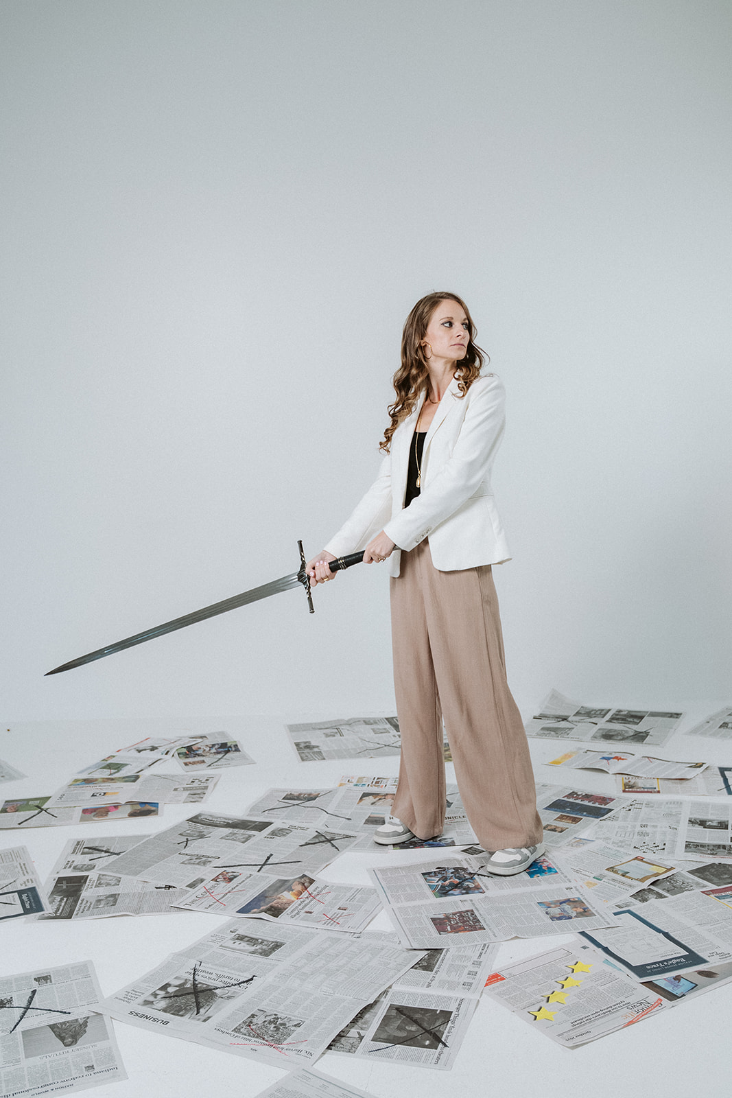 Traci standing on scattered newspapers with a sword raised at her side
