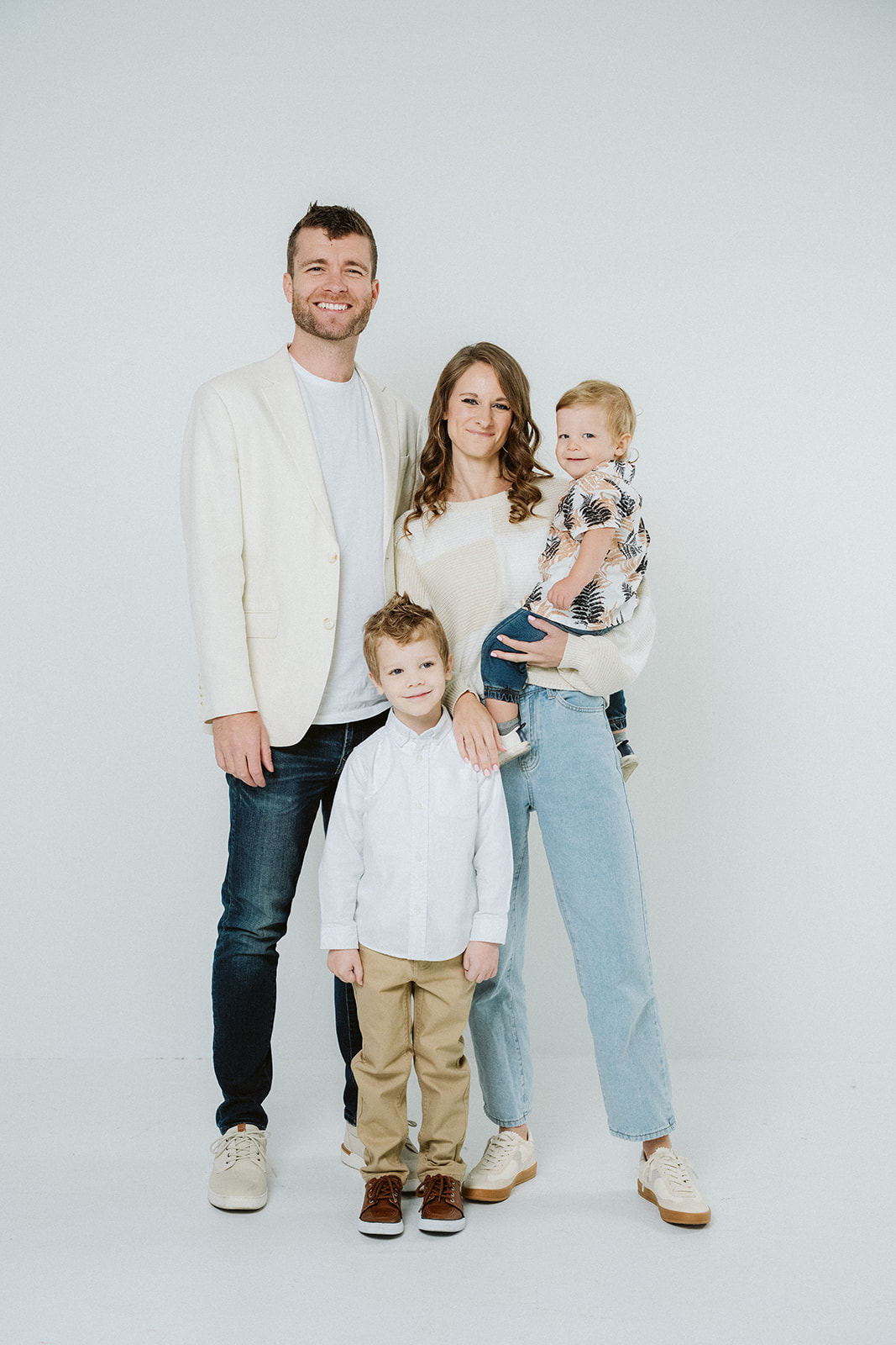 Coston family of four standing together in the studio, parents with their two young sons