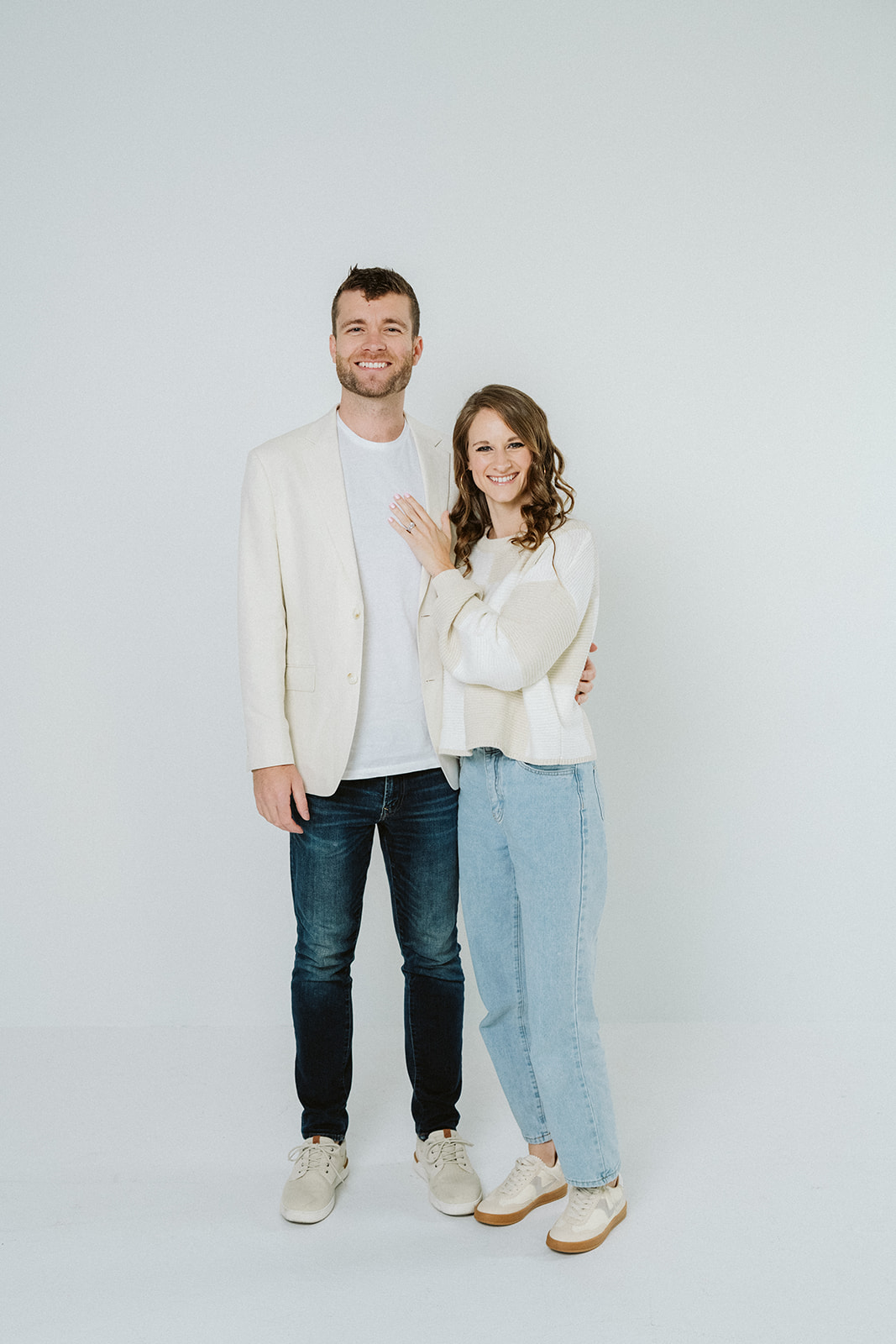 Traci and her husband standing together against a bright studio backdrop