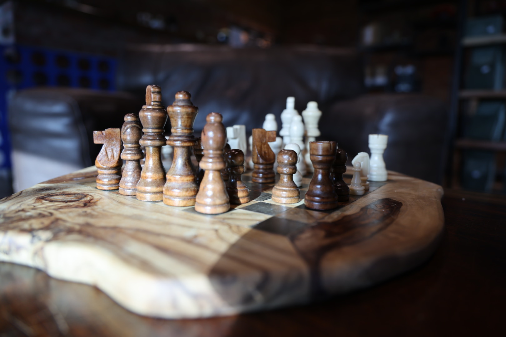 Olive-wood chess board with wooden and stone pieces mid-game