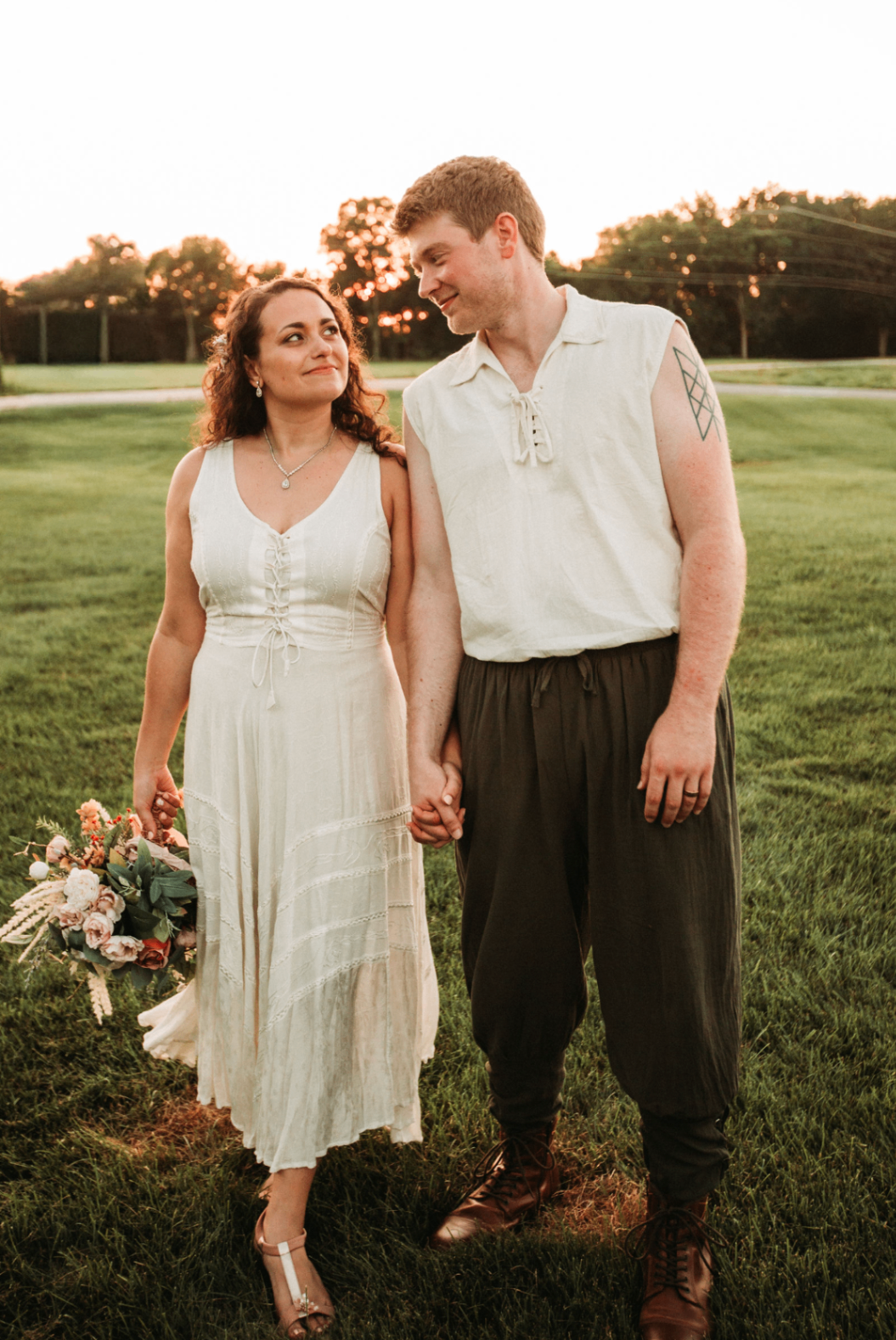 Jessie and Kurtis walking hand in hand across the grass at sunset