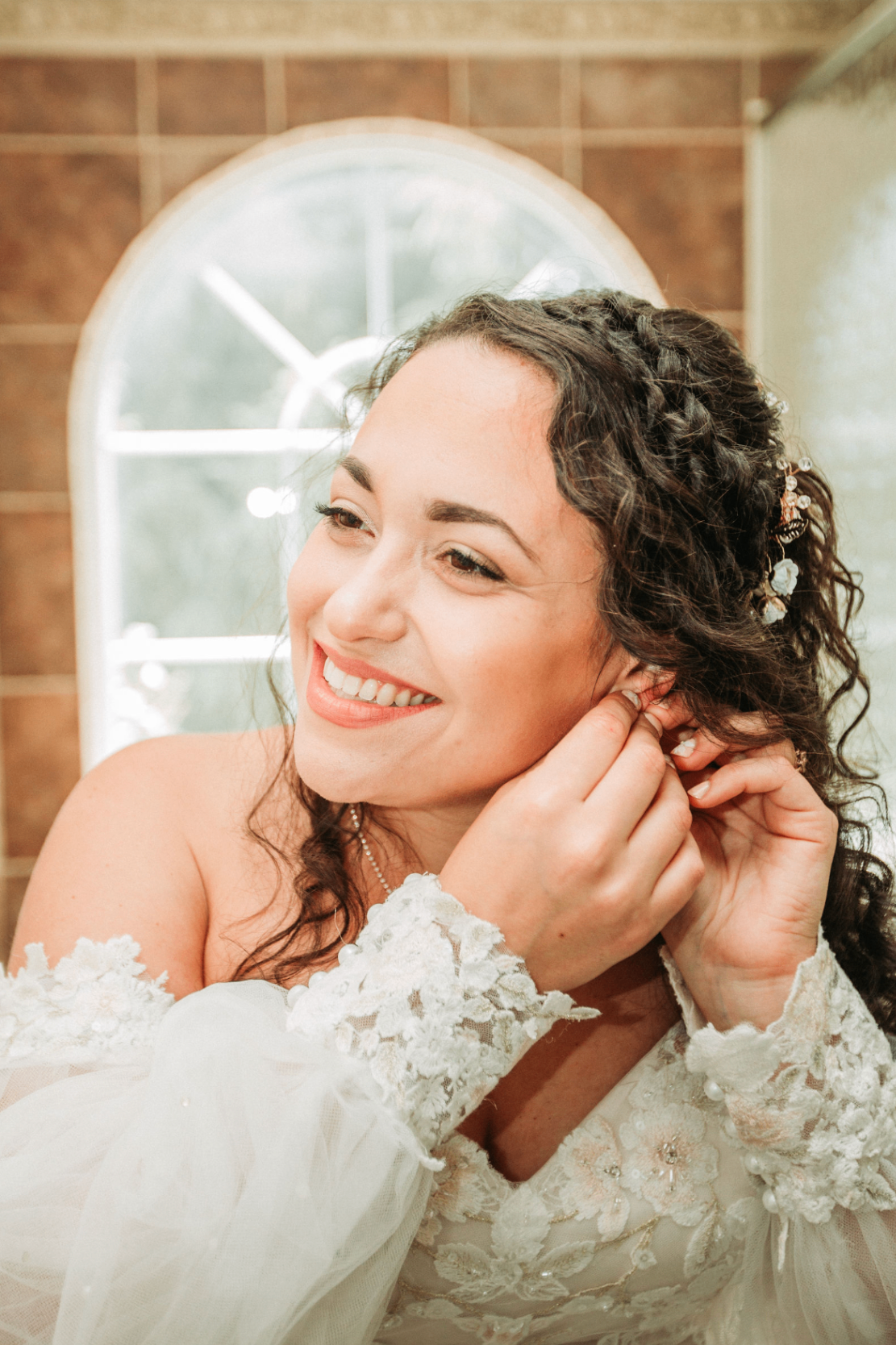 Jessie laughing while putting in her earring in front of an arched window