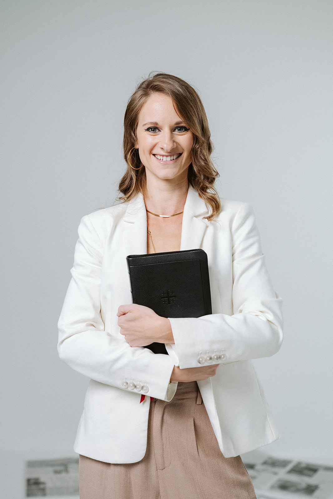 Traci in a white blazer holding a black Bible close to her chest