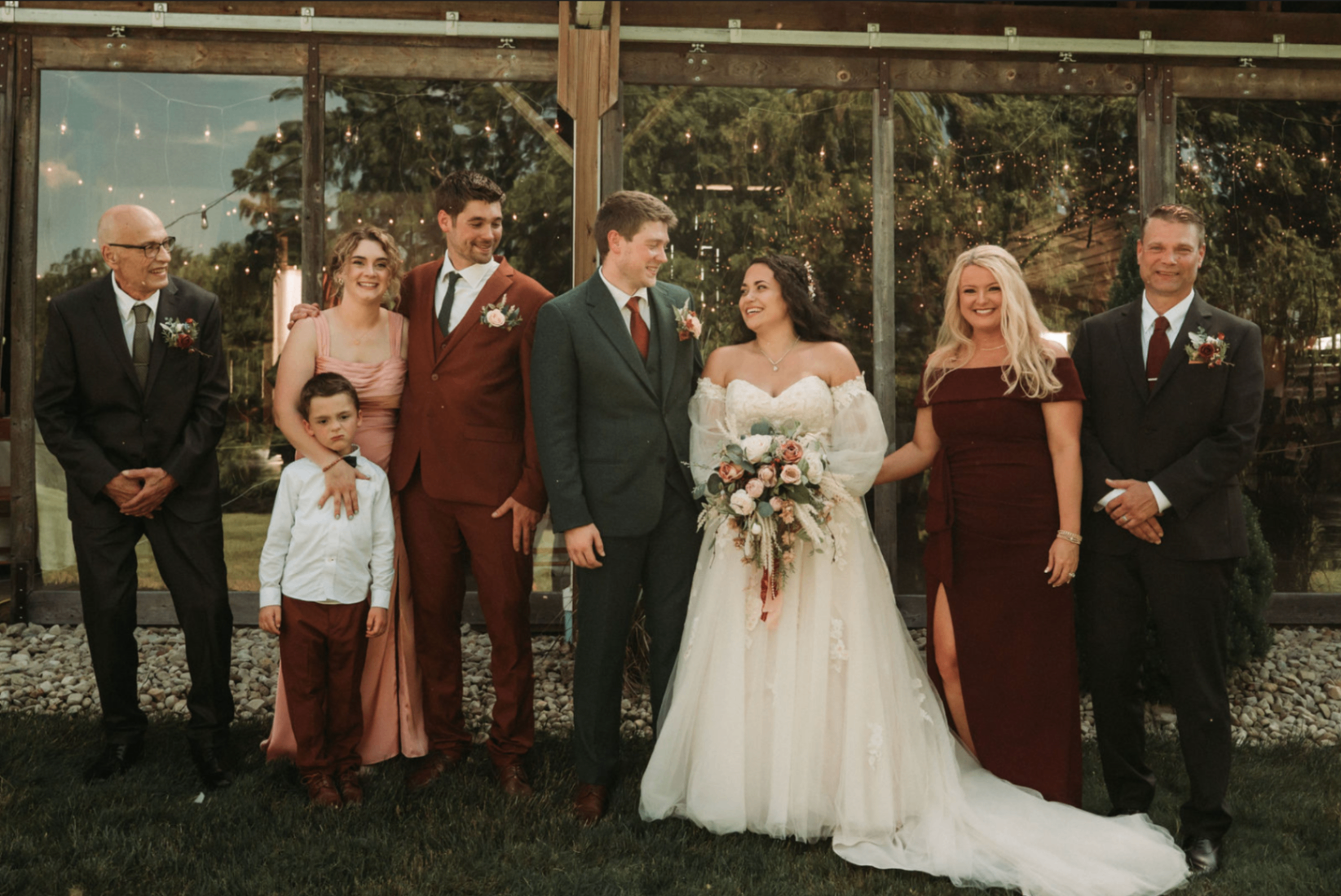 Jessie and Kurtis with family members posed outside the reception barn at dusk