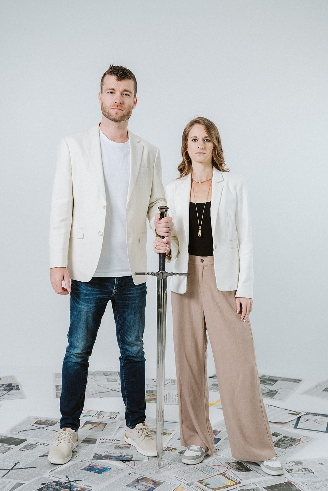 Traci and her husband standing together on newspapers, sword point down between them