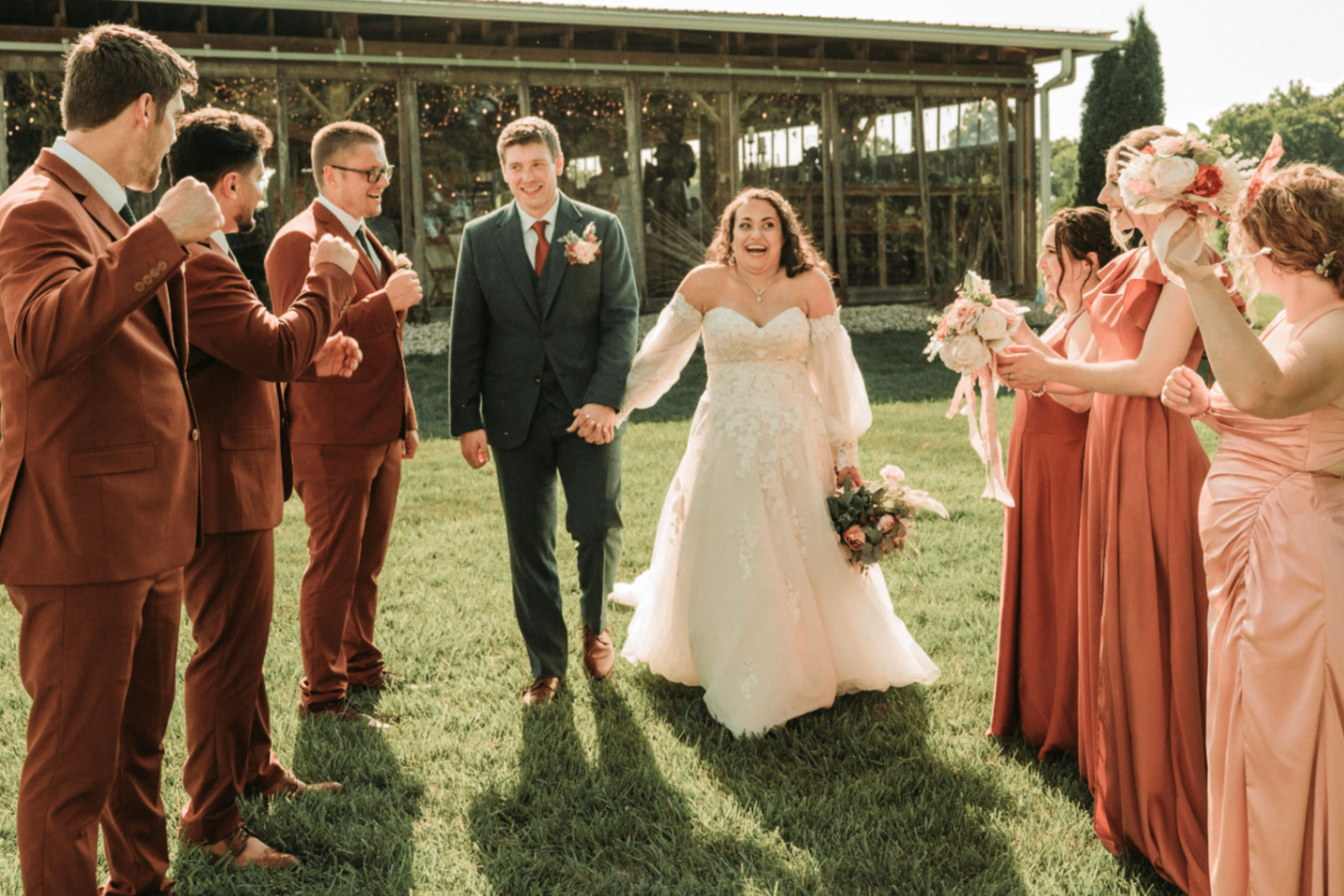 Jessie and Kurtis walking through a cheering wedding party on the grass