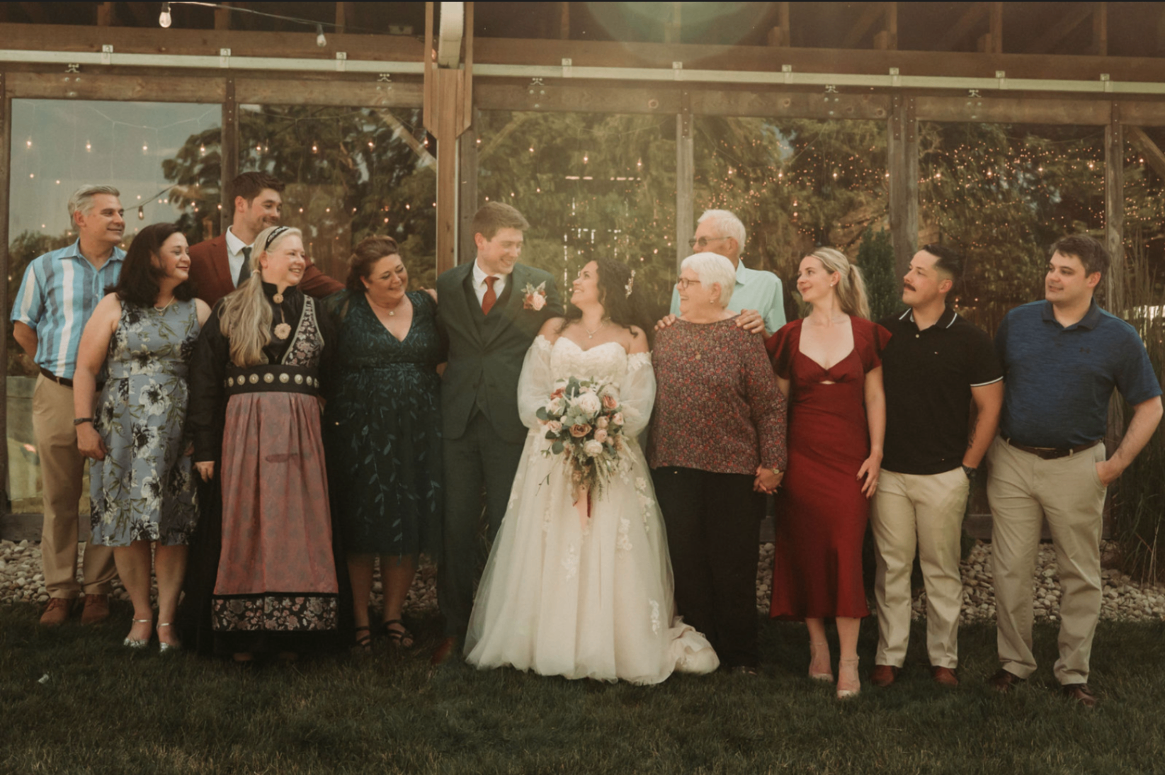 Jessie and Kurtis with a large family group outside the reception barn in the evening light