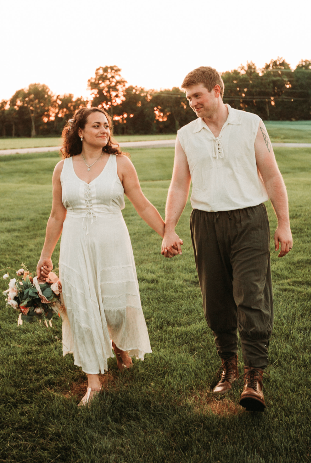 Jessie and Kurtis walking across the field with bouquet in hand