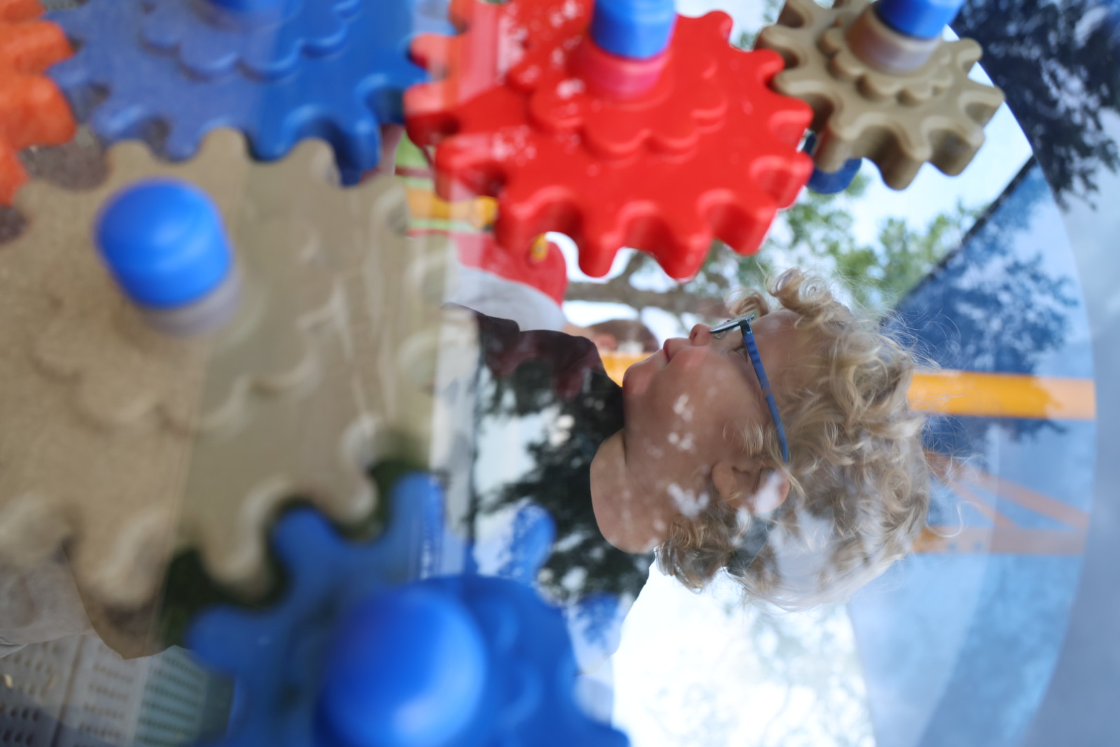 Boy behind a spinning wall of red, blue, and tan gears