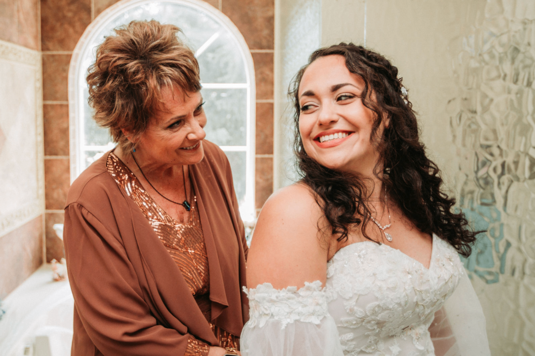 Jessie smiling over her shoulder while an older woman helps her get ready