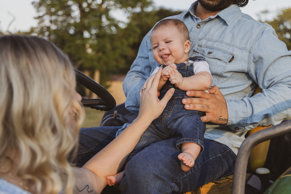 Smiling family gathered around their baby outdoors